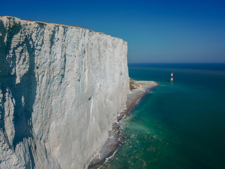 tall chalk cliffs towering over a lighthouse